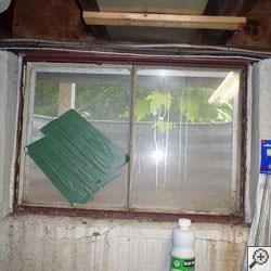 An old, rusted basement window with a steel frame in Mount Vernon.